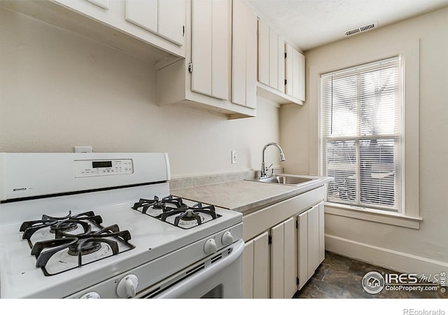 kitchen featuring sink, white gas range oven, and white cabinets