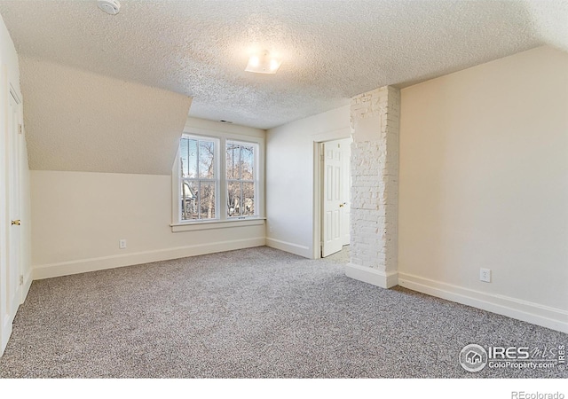 additional living space featuring vaulted ceiling, carpet, and a textured ceiling