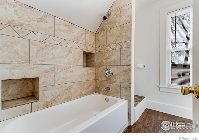 bathroom featuring tiled shower / bath, vaulted ceiling, and wood-type flooring