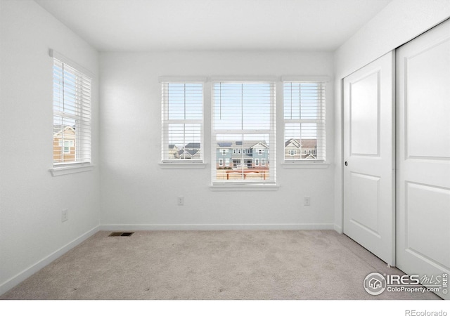 unfurnished bedroom with light colored carpet and a closet