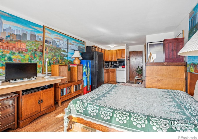 bedroom featuring black fridge and light hardwood / wood-style floors