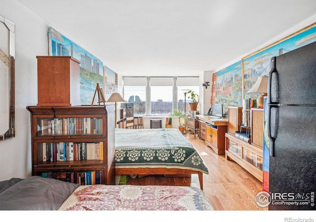 bedroom featuring light hardwood / wood-style floors and black fridge