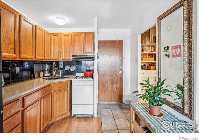 kitchen with white gas range, backsplash, and sink