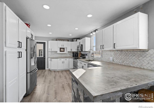 kitchen with white cabinetry, stainless steel appliances, and kitchen peninsula