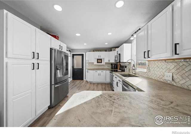 kitchen featuring sink, white cabinetry, stainless steel appliances, tasteful backsplash, and light hardwood / wood-style floors