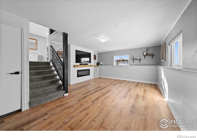 unfurnished living room with ornamental molding, a textured ceiling, and light wood-type flooring