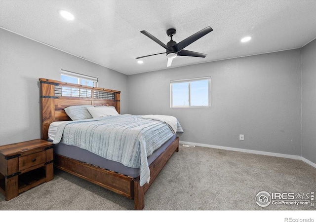 bedroom featuring light carpet, multiple windows, and a textured ceiling