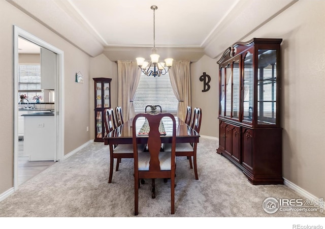 dining room with light carpet, a tray ceiling, and a chandelier