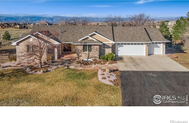 view of front facade featuring a garage, a mountain view, and a front lawn