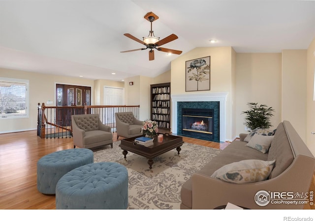 living room featuring a high end fireplace, lofted ceiling, and light hardwood / wood-style floors