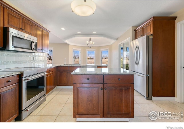 kitchen featuring stainless steel appliances, light tile patterned flooring, a kitchen island, and kitchen peninsula