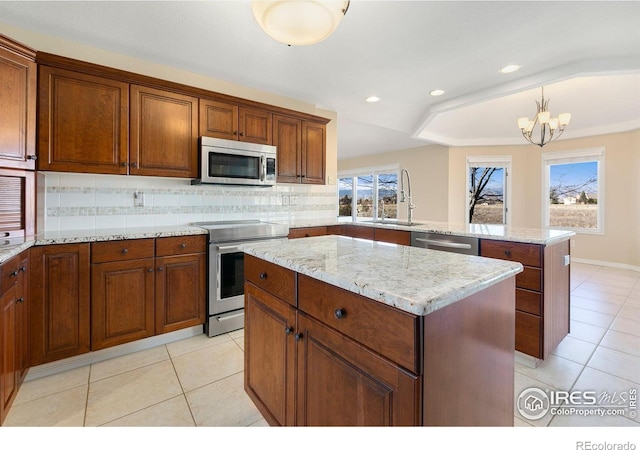 kitchen with appliances with stainless steel finishes, pendant lighting, sink, a center island, and kitchen peninsula