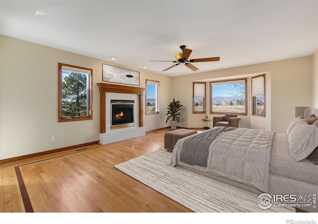 bedroom featuring ceiling fan, multiple windows, and light wood-type flooring