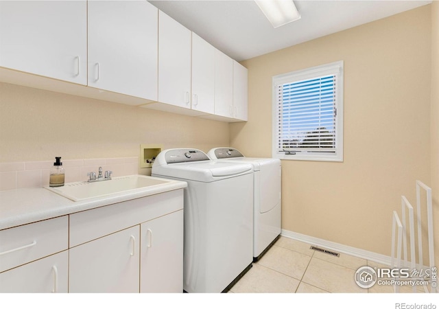 washroom featuring sink, light tile patterned floors, cabinets, and independent washer and dryer