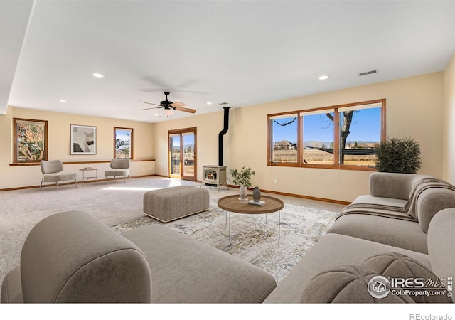 living room with carpet, ceiling fan, and a wood stove