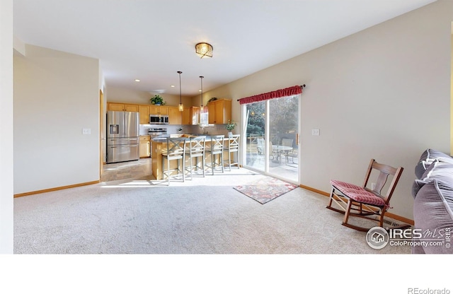 kitchen featuring a breakfast bar area, light carpet, hanging light fixtures, appliances with stainless steel finishes, and a kitchen island