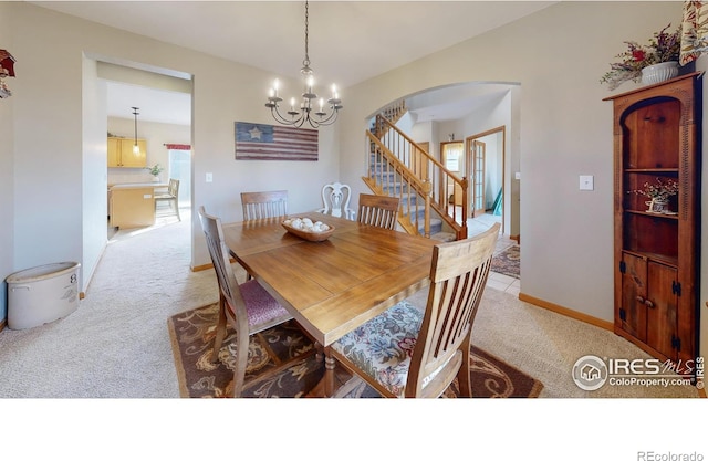 dining room featuring light colored carpet and an inviting chandelier