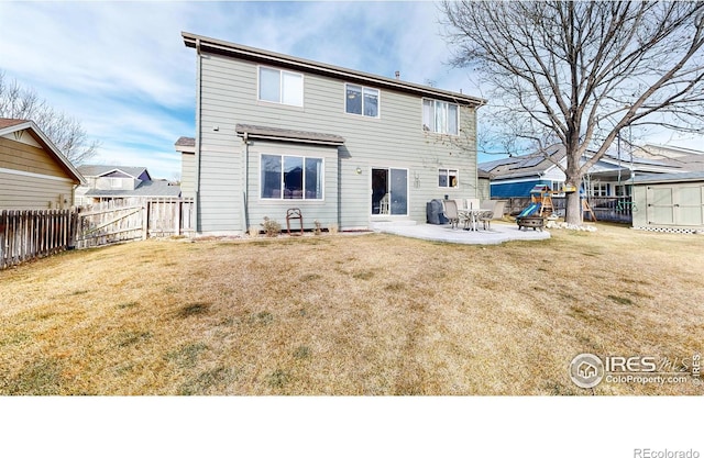 rear view of property featuring a yard, a storage unit, and a patio