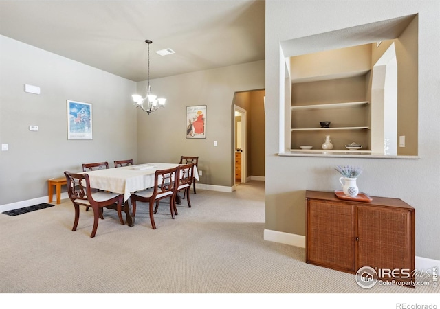 dining room featuring a notable chandelier, built in shelves, and light colored carpet