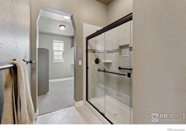 bathroom with tile patterned flooring and a shower with shower door