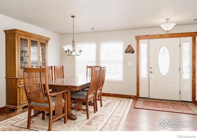 dining room with light wood-style flooring, baseboards, and a notable chandelier