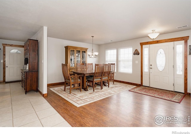 dining space with light wood-type flooring, visible vents, a notable chandelier, and baseboards