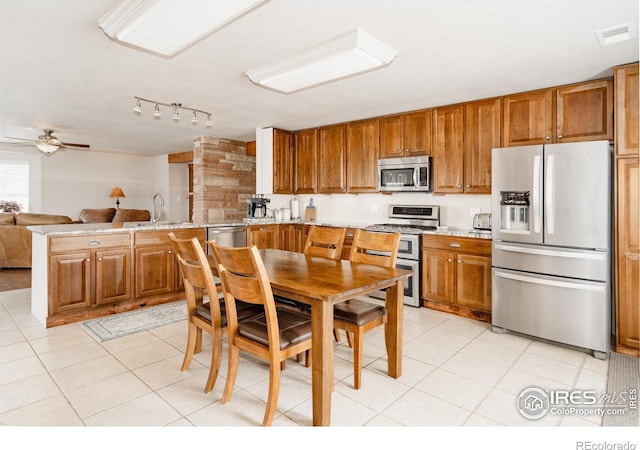 kitchen with visible vents, appliances with stainless steel finishes, brown cabinetry, a sink, and a peninsula