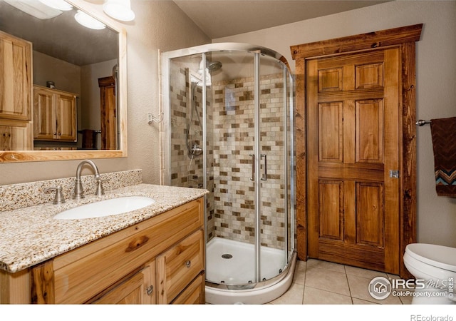 full bathroom featuring a stall shower, vanity, toilet, and tile patterned floors