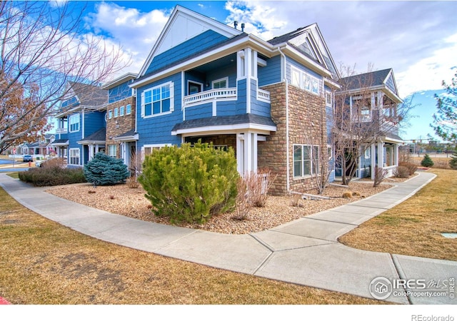 view of front of home with a balcony and a front lawn