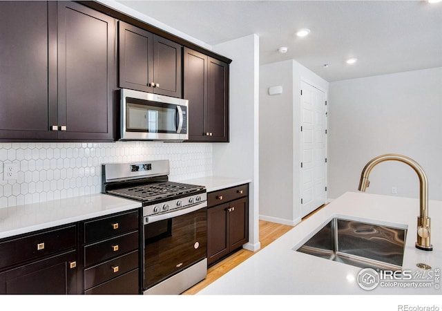 kitchen with sink, backsplash, dark brown cabinetry, stainless steel appliances, and light hardwood / wood-style flooring