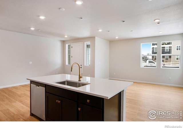 kitchen featuring dishwasher, sink, an island with sink, and light hardwood / wood-style floors