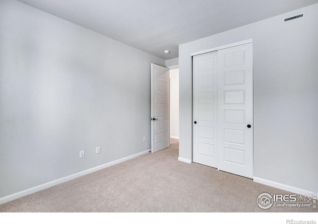 unfurnished bedroom with light carpet and a closet