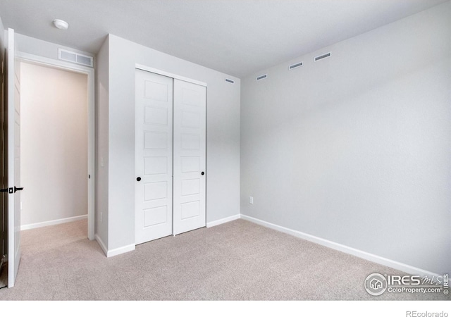 unfurnished bedroom with light colored carpet and a closet