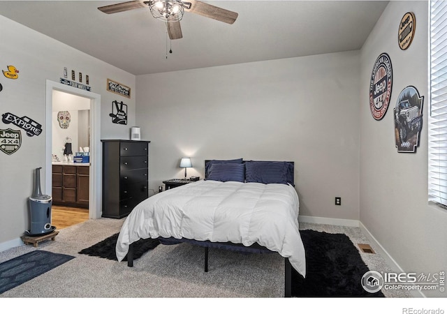 bedroom with ceiling fan, light colored carpet, and ensuite bath