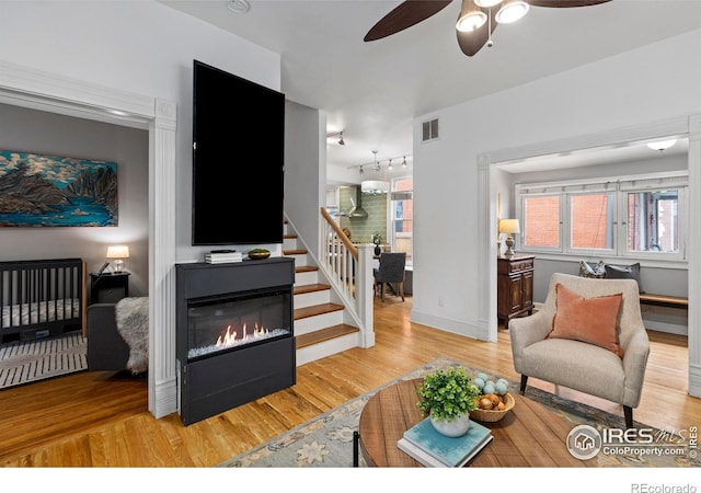 living room featuring rail lighting, ceiling fan, and light wood-type flooring