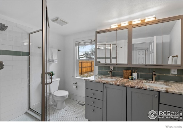 bathroom with tile patterned flooring, backsplash, vanity, a shower with shower door, and toilet