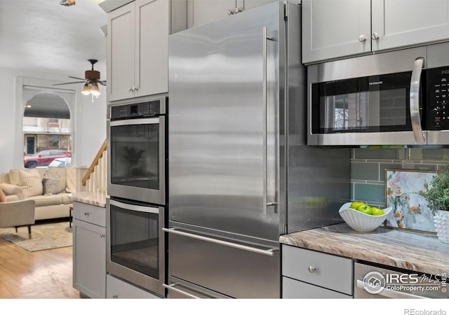 kitchen with light hardwood / wood-style flooring, gray cabinets, ceiling fan, stainless steel appliances, and decorative backsplash