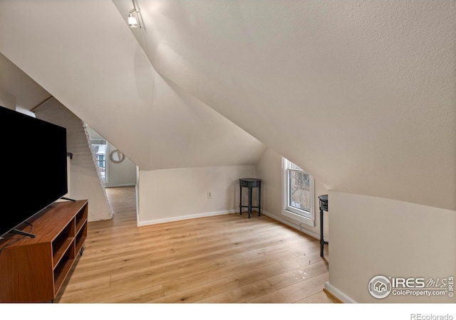 bonus room with vaulted ceiling and light hardwood / wood-style floors