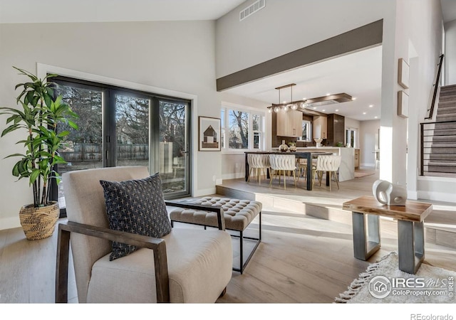 living room with a towering ceiling and light hardwood / wood-style floors