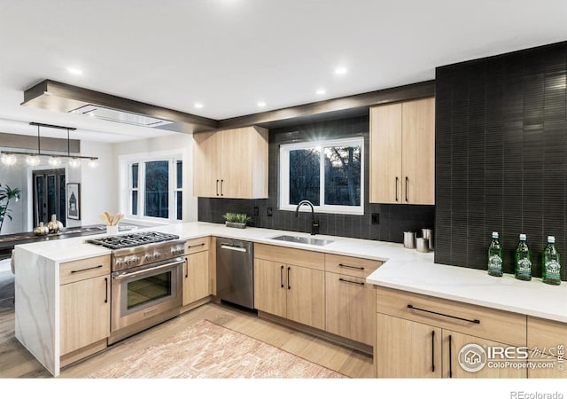 kitchen with sink, light hardwood / wood-style flooring, light brown cabinets, kitchen peninsula, and stainless steel appliances