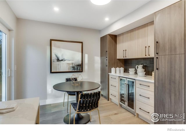 kitchen featuring backsplash, light hardwood / wood-style flooring, beverage cooler, and light brown cabinets