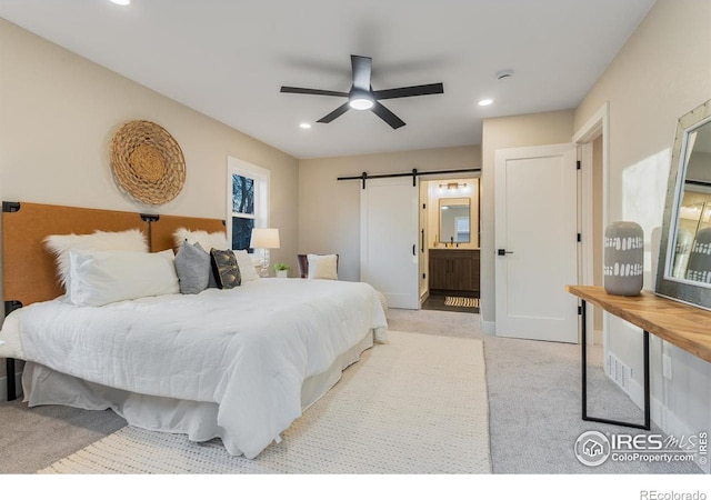 carpeted bedroom featuring ceiling fan, ensuite bathroom, and a barn door