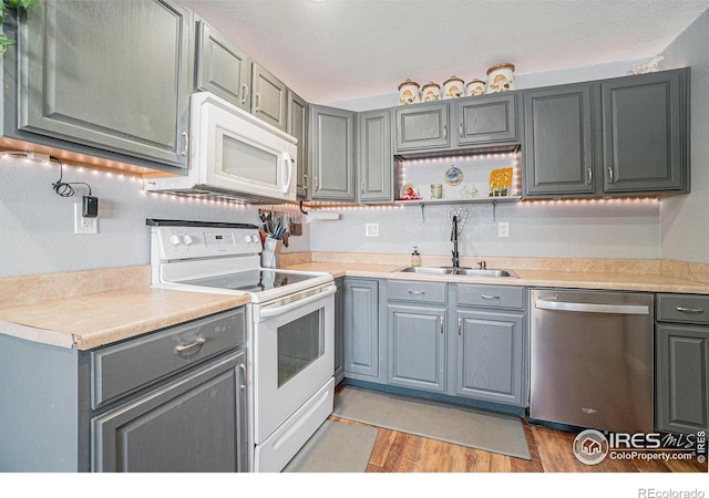 kitchen featuring sink, white appliances, and light hardwood / wood-style flooring