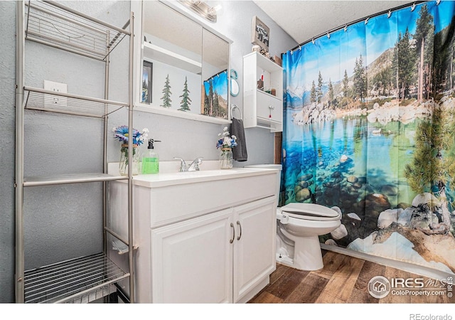 bathroom with toilet, a textured ceiling, vanity, a shower with shower curtain, and hardwood / wood-style flooring