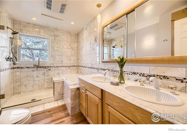 bathroom featuring tile walls, vanity, tasteful backsplash, wood-type flooring, and shower with separate bathtub