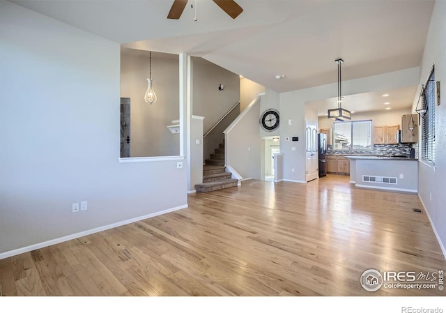 unfurnished living room featuring ceiling fan and light wood-type flooring