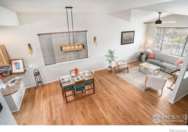living area with baseboards, ceiling fan, light wood finished floors, and lofted ceiling
