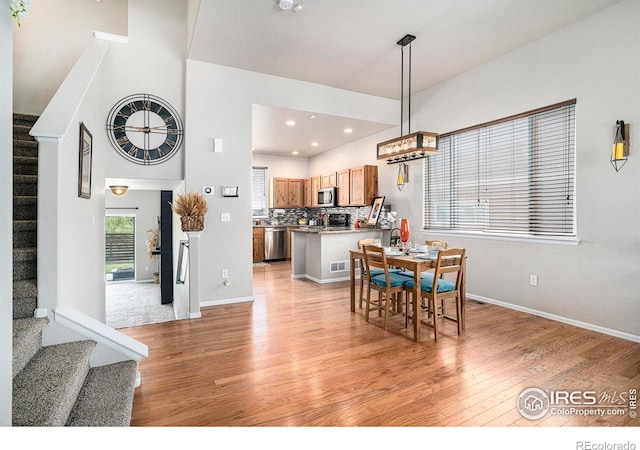 dining room with recessed lighting, baseboards, stairway, and light wood-type flooring