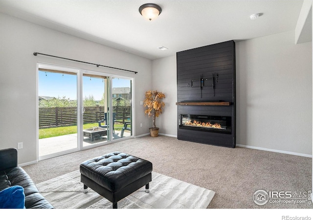 living area featuring baseboards, carpet, and a large fireplace