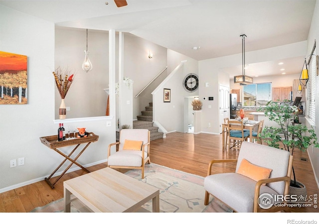 living area with baseboards, stairs, and wood finished floors